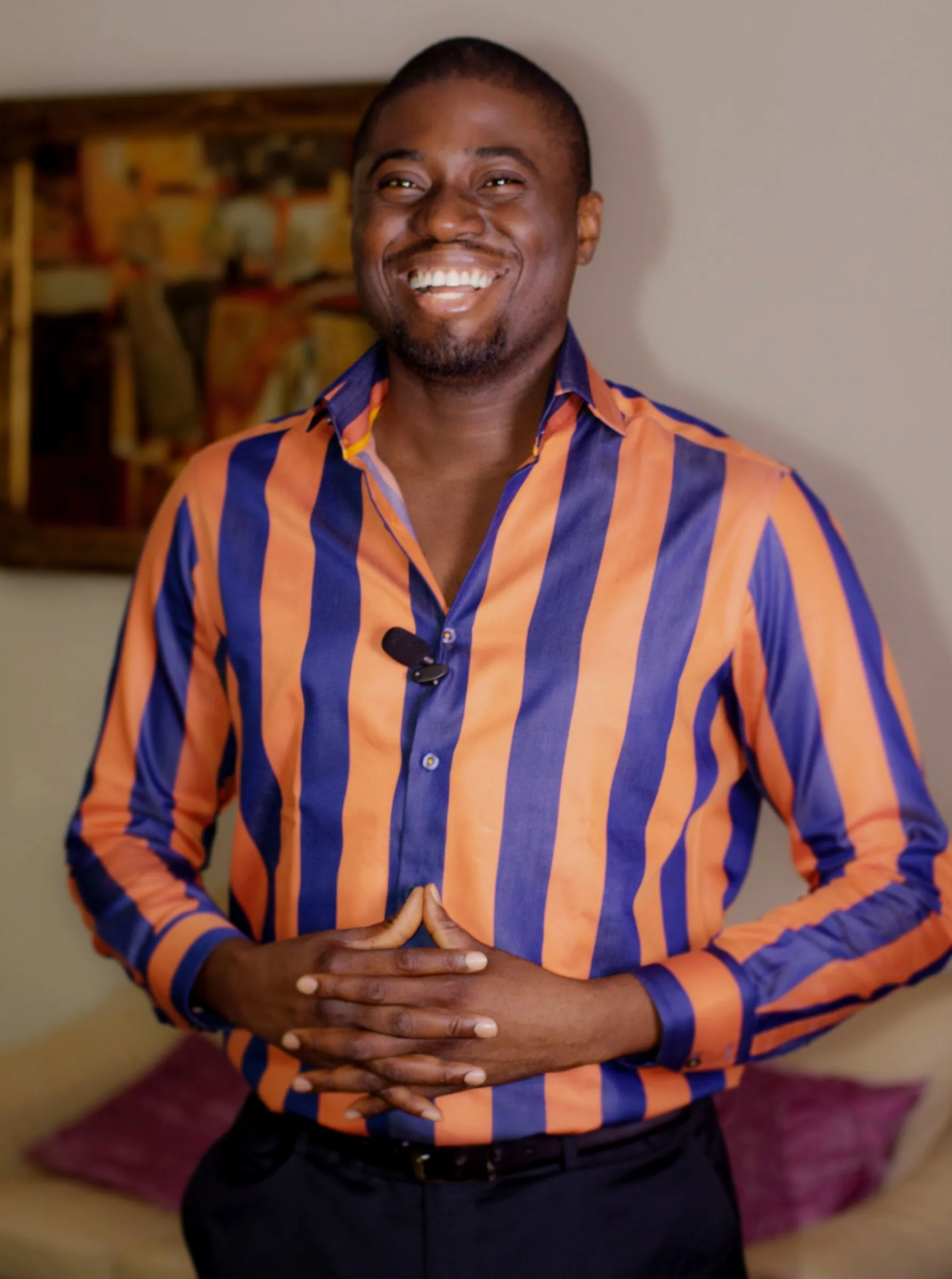 Chi Odogwu smiling, wearing a lapel mic and a striped shirt