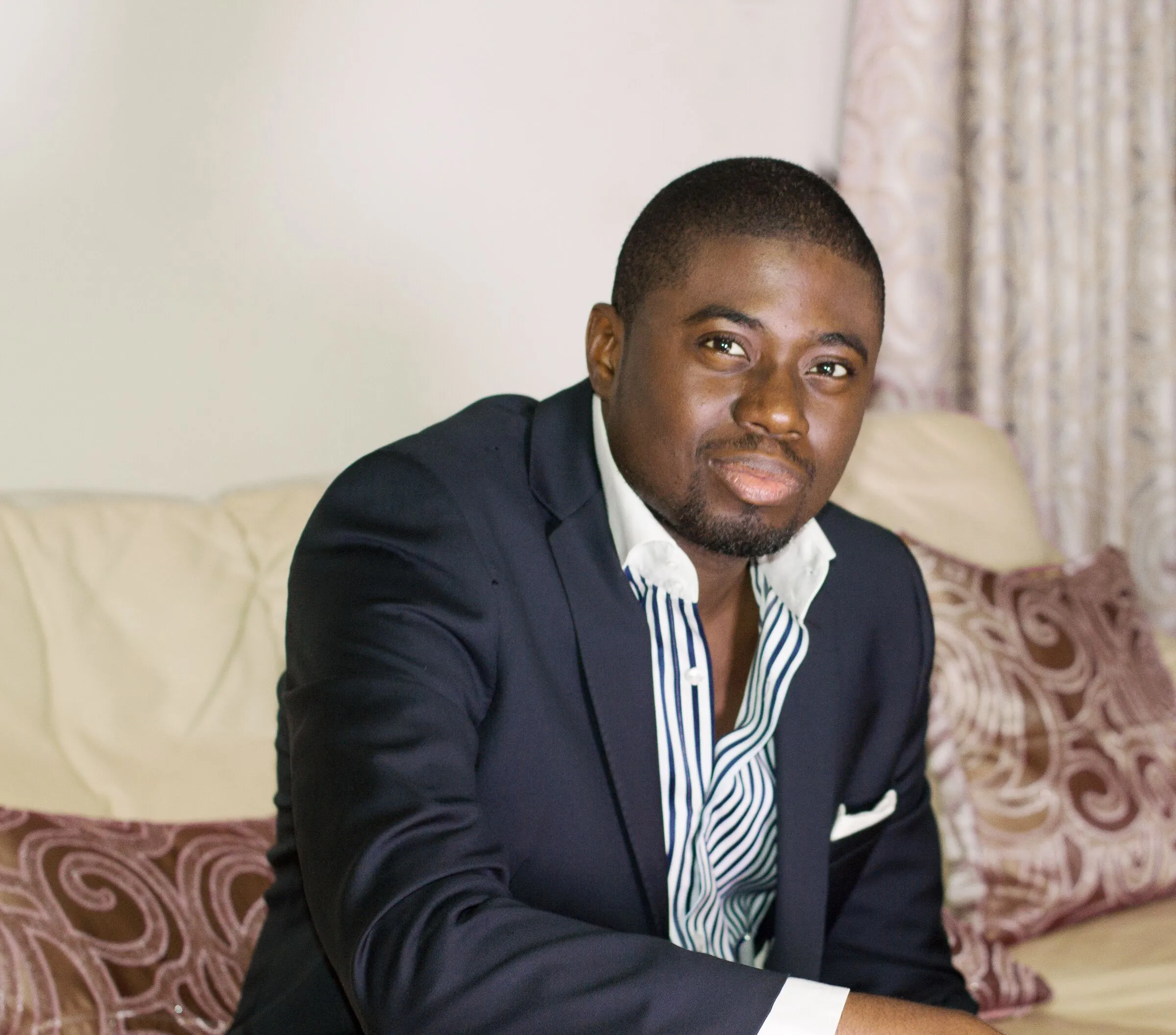 Chi Odogwu leaning forward on a cream sofa
